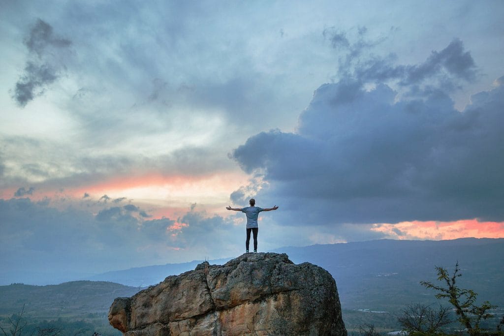 How to get success in life person on rock in front of clouds