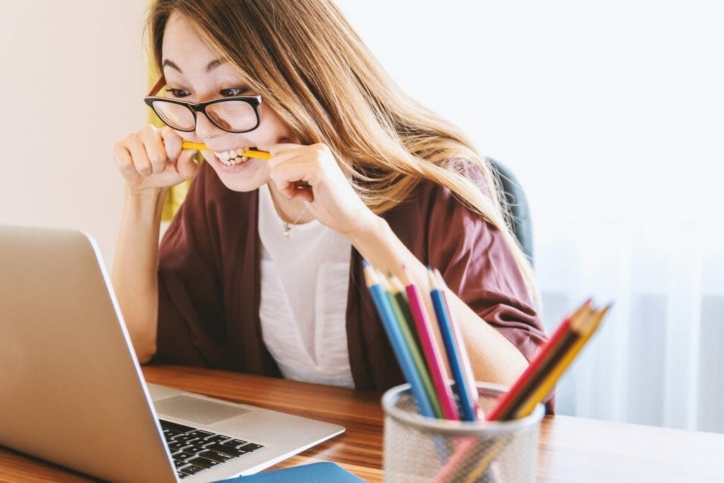 How to start studying and stop procrastinating - student chewing pencil while looking at laptop